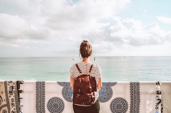 Girl with a backpack in front of the ocean