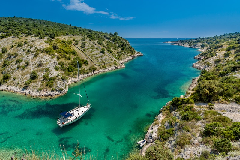 Sailboat sailing between two pieces of land in Trogir, Croatia 