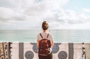 Girl with a backpack in front of the ocean