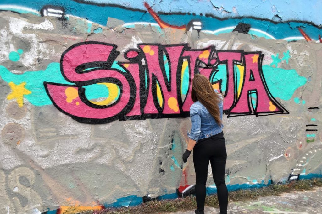 Girl doing graffiti around Berlin wall.