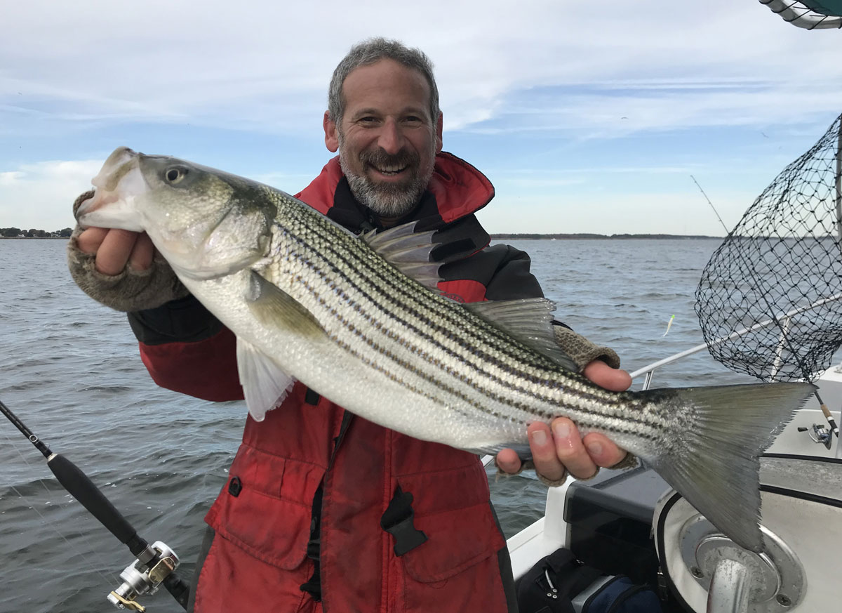 Lenny Rudow fishing on his boat with a Chesapeake Bay striped bass.