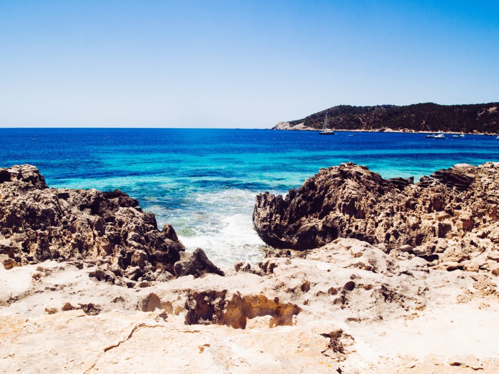 View of the Ses Salines beach in Ibiza, showing the rocks on the coast and the clear water in the background