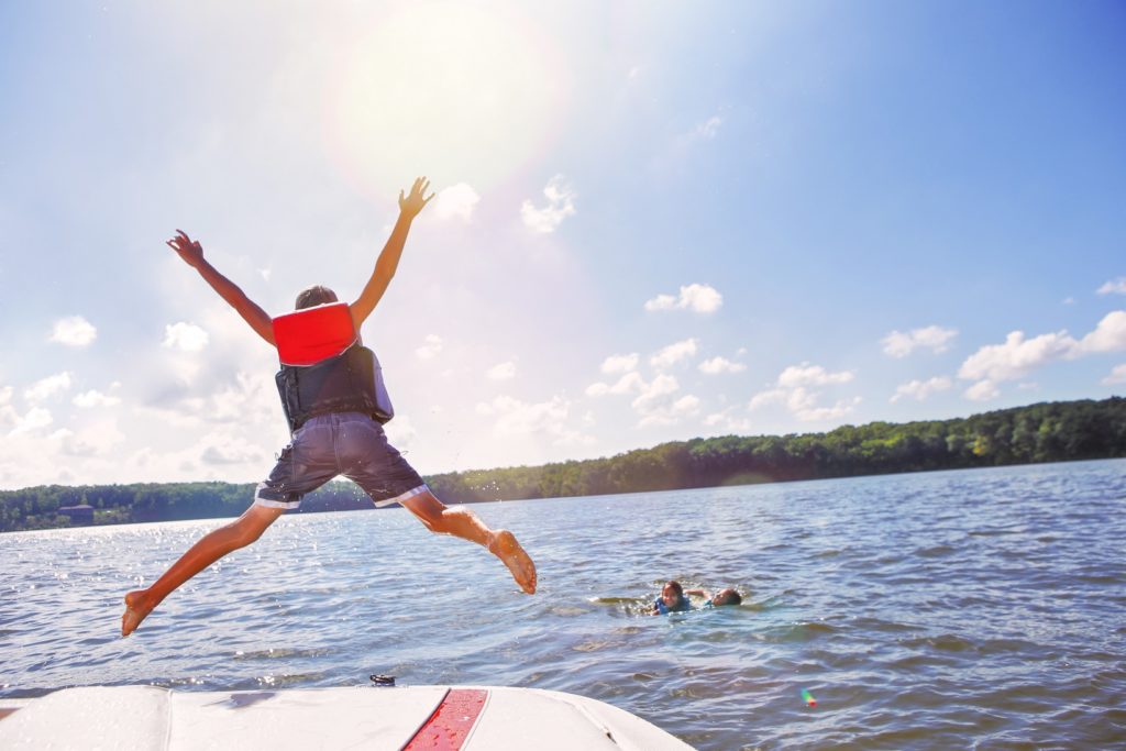 View of a kid jumping in the water from a boat.