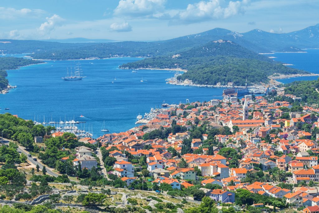An aerial view of Mali Losinj presenting the buildings on land, the port and the surrounding islands