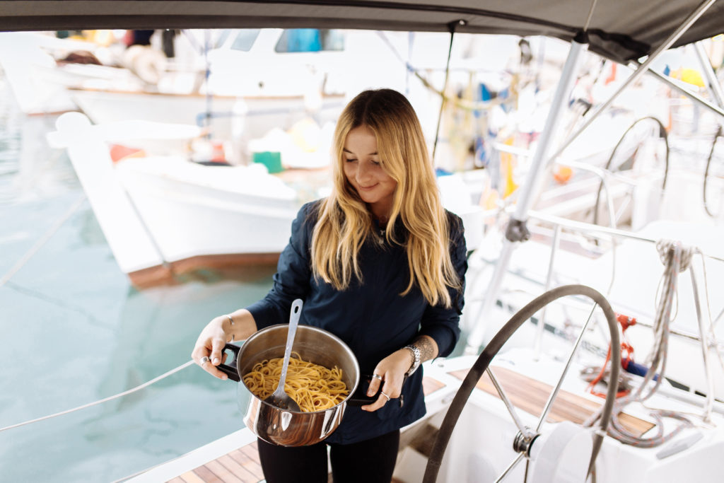 View of a woman on a boat with a pot of pasta in her hand