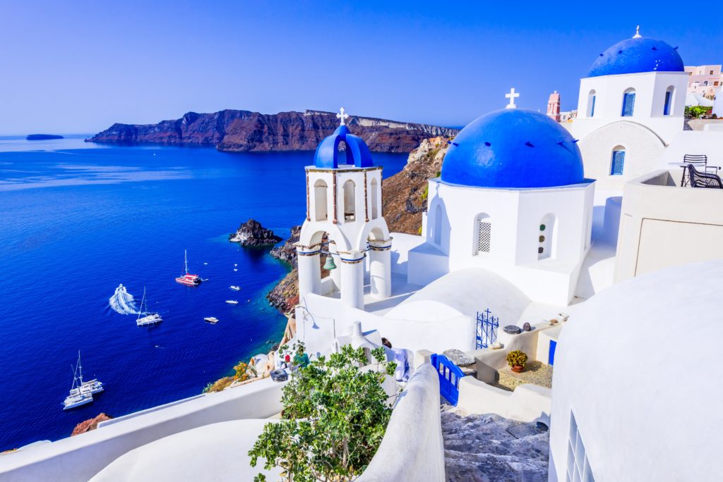 Aerial view of the whitewashed buildings on the side of the cliffs in Greece and the blue water