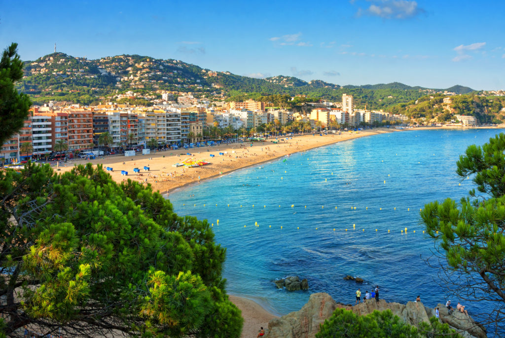 View of the bay in Lloret de Mar with sandy beach and the surrounding buildings and trees