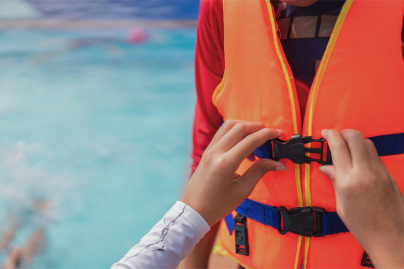 Passenger fastening a life jacket before a boat excursion
