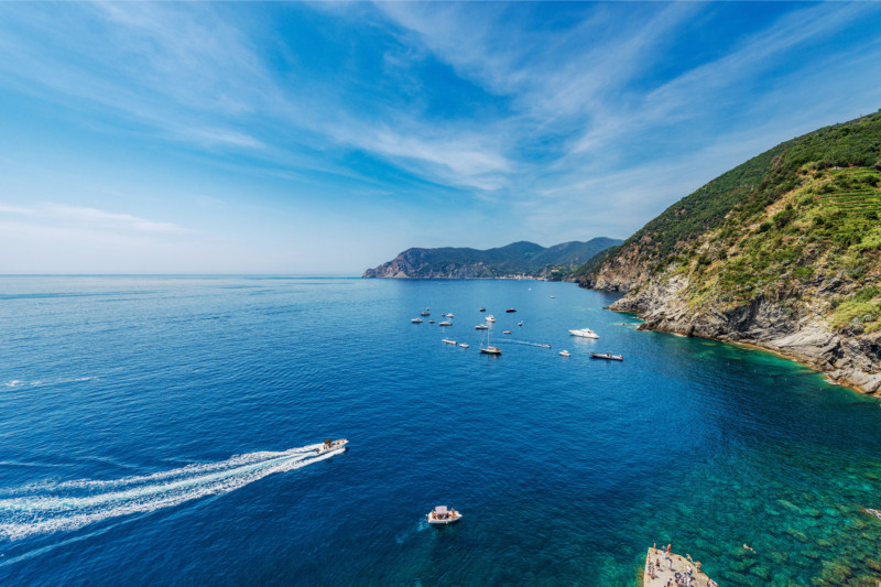Panoramic view of a bay surrounded by cliffs with several boats navigating offshore